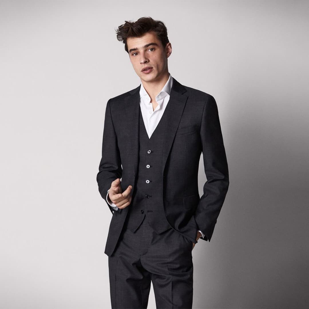 Detailed shot of a sleek black tuxedo jacket with an embroidered company logo on the chest, symbolizing high quality branding.