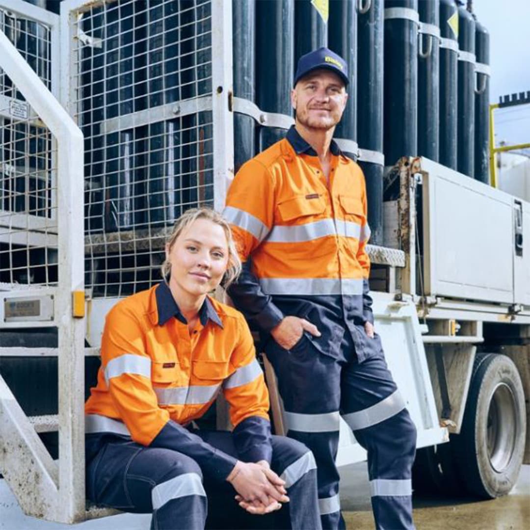 A photograph showcasing a variety of uniforms made from durable fabrics in a warehouse setup.